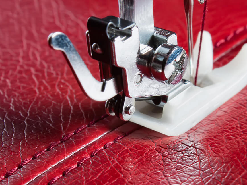 Close up of sewing machine needle on red leather